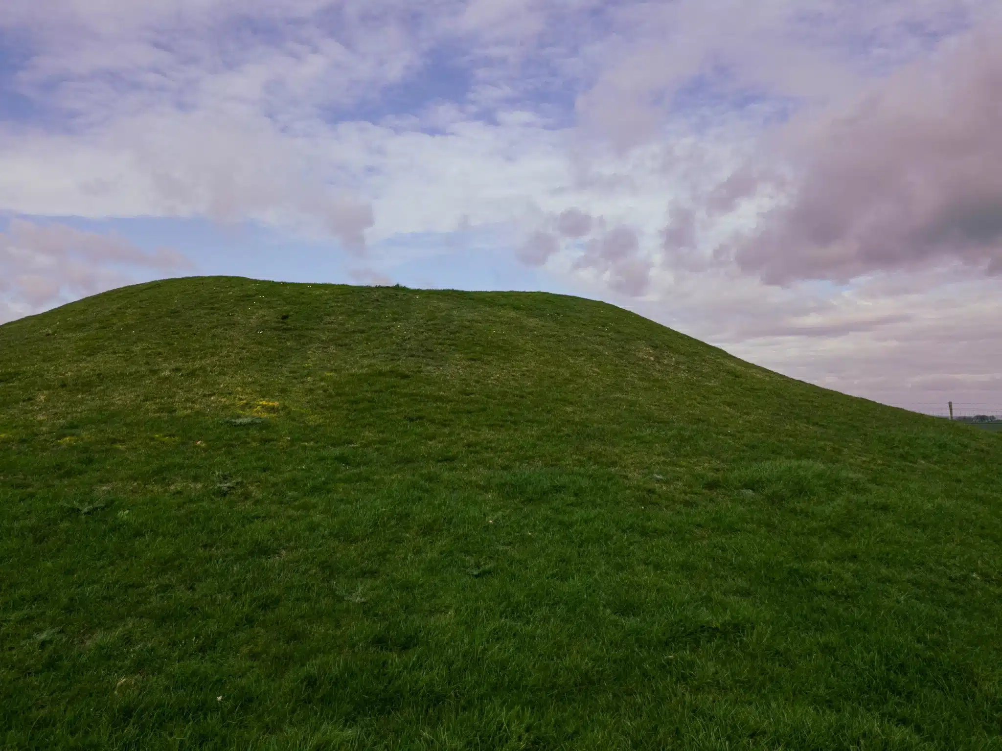 Grassy hill under a cloudy sky at sunset for green burial services in costa mesa california