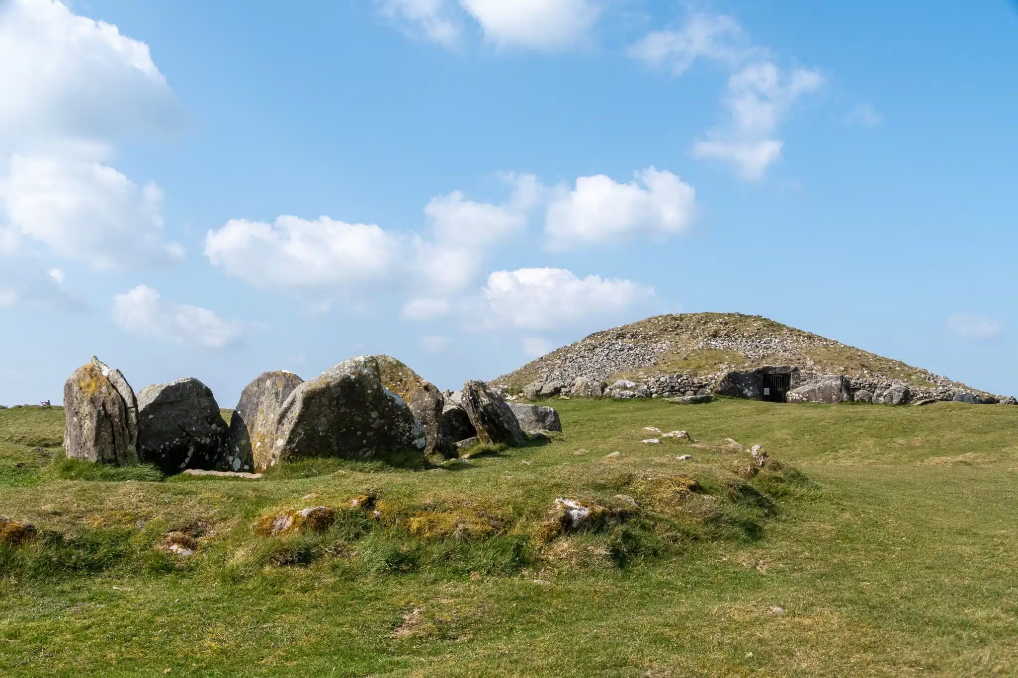 Ancient stone burial mound in lush green field for Green Burial Services in Solano County, California