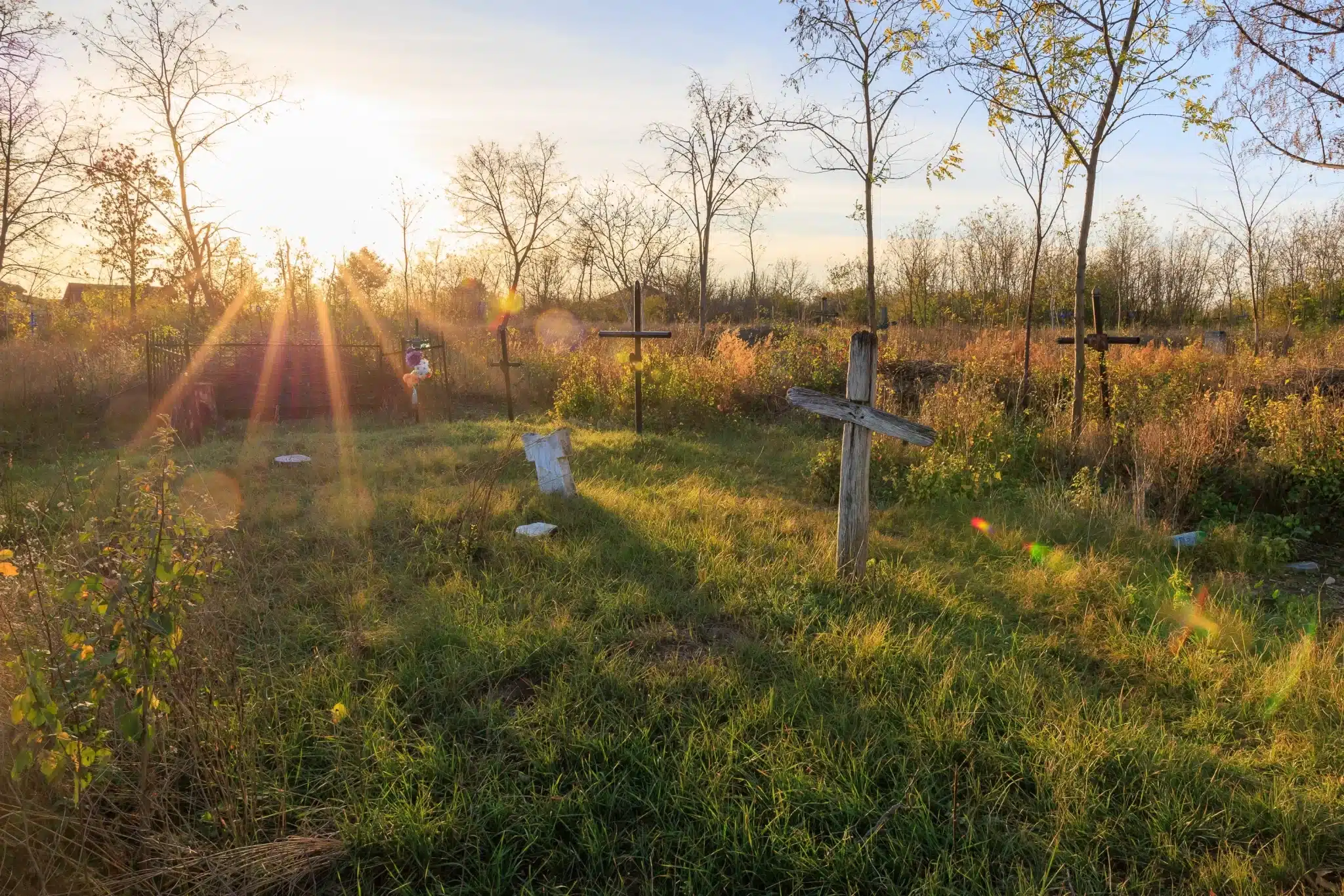 Sunset over rural cemetery with wooden crosses for