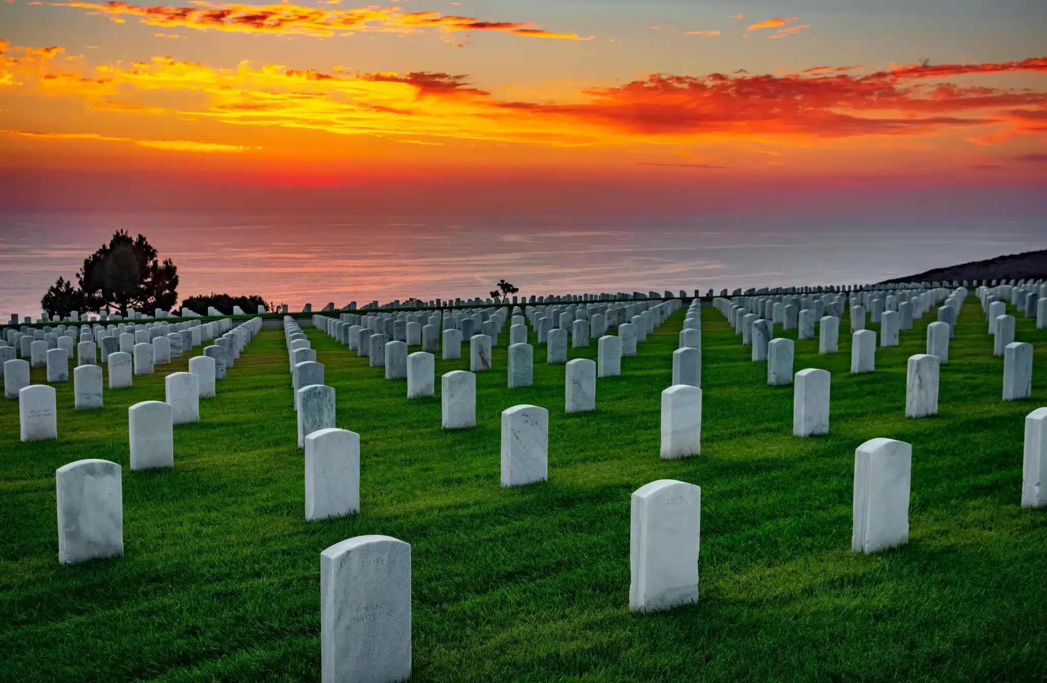 Sunset over ocean-facing military cemetery with white headstones for Green Burial Services in Santa Clara County, California