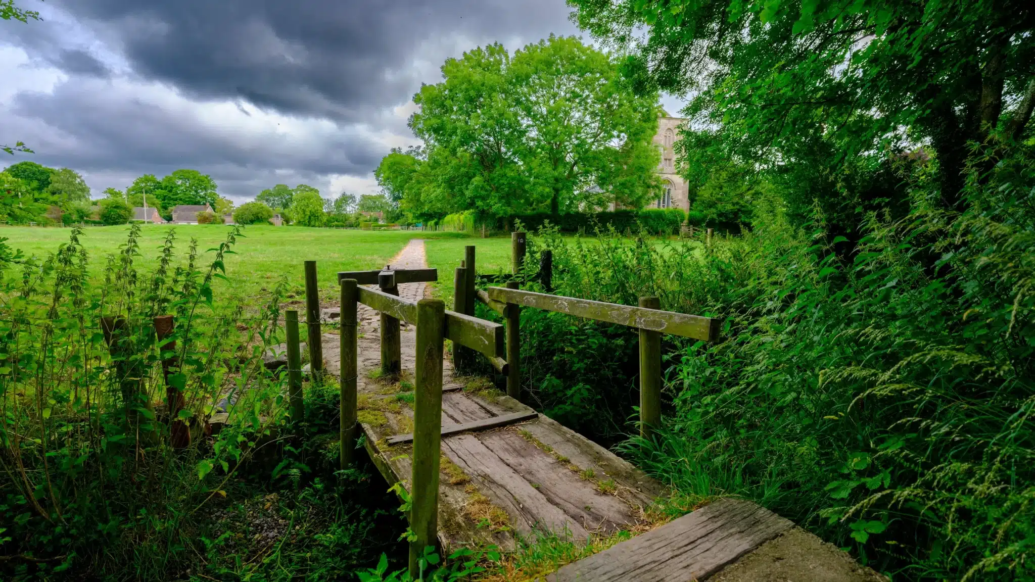 Wooden footbridge in lush green rural landscape for Green Burial Services in Alameda County, California